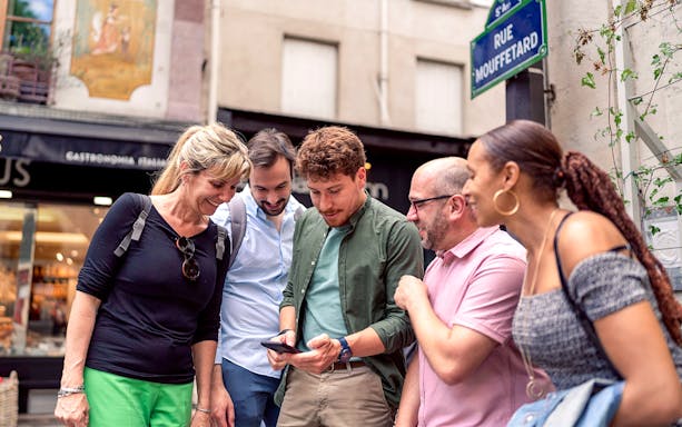 Group of tourists on Rue Mouffetard during a guided walking tour in Paris's Latin Quarter.