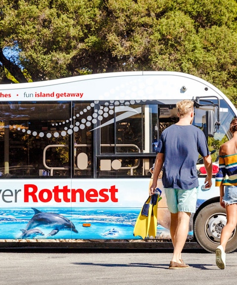 Couple walking towards Rottnest Island tour bus with snorkel gear.