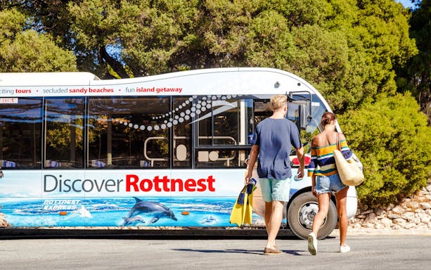 Couple walking towards Rottnest Island tour bus with snorkel gear.