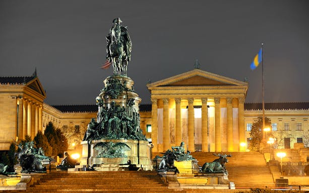 Philadelphia Museum of Art at night with Washington Monument in foreground.