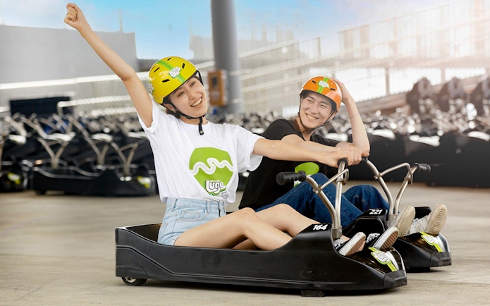 Two people enjoying a ride at Skyline Luge Busan, wearing helmets and smiling.