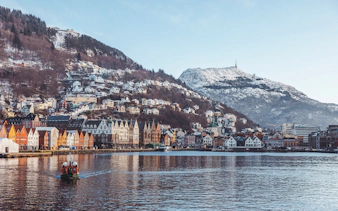 Bryggen harbor with colorful buildings and snow-covered mountains in Bergen, Norway.