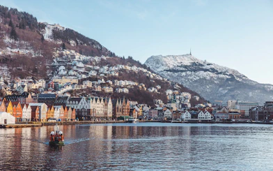 Bryggen harbor with colorful buildings and snow-covered mountains in Bergen, Norway.