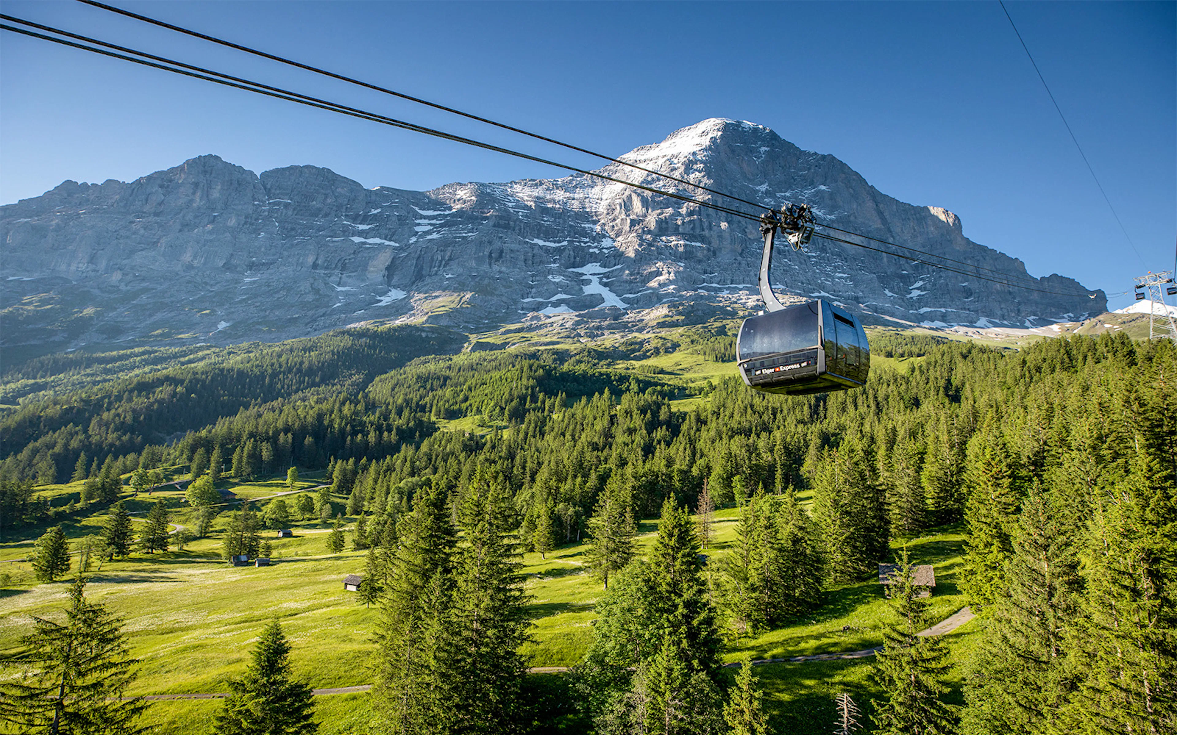 Eiger Express cable car ascending with Swiss Alps backdrop.