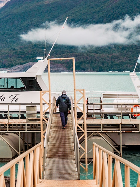 Person walking towards Perito Moreno cruise boarding point with glacier in background.
