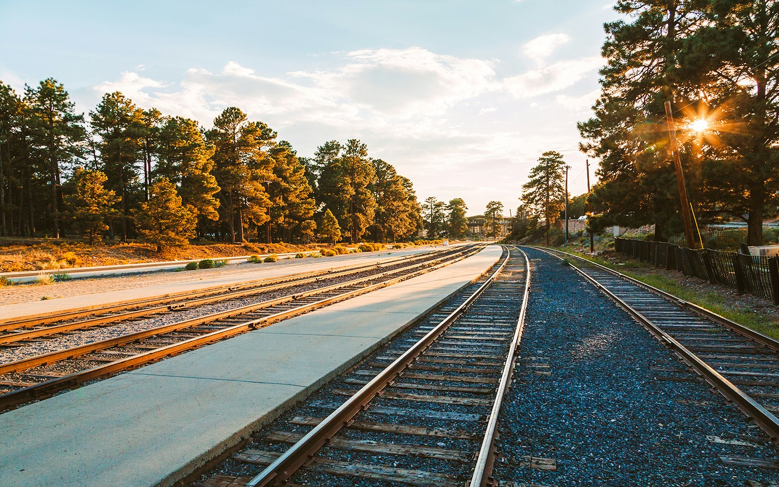 Railroad tracks at Grand Canyon Village surrounded by trees at sunset.