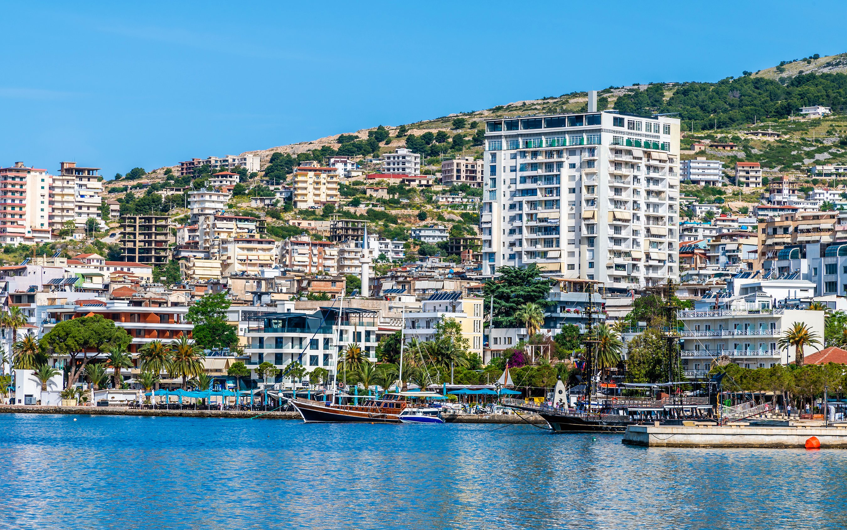 Buildings along the bay in Sarande, Albania, with boats docked in the morning.