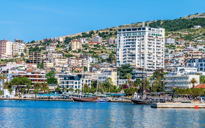 Buildings along the bay in Sarande, Albania, with boats docked in the morning.