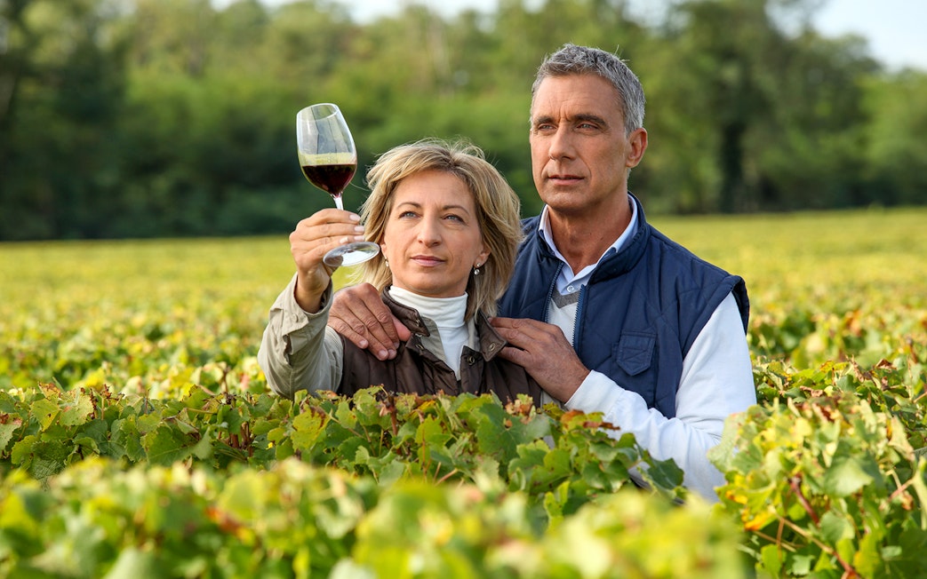 Couple examining wine in a vineyard during a wine tour.