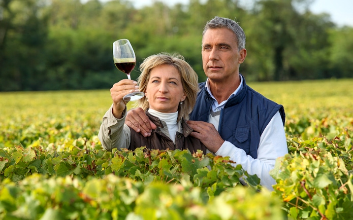 Couple examining wine in a vineyard during a wine tour.
