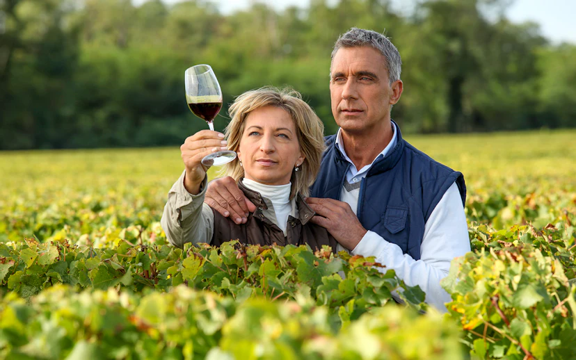 Couple examining wine in a vineyard during a wine tour.