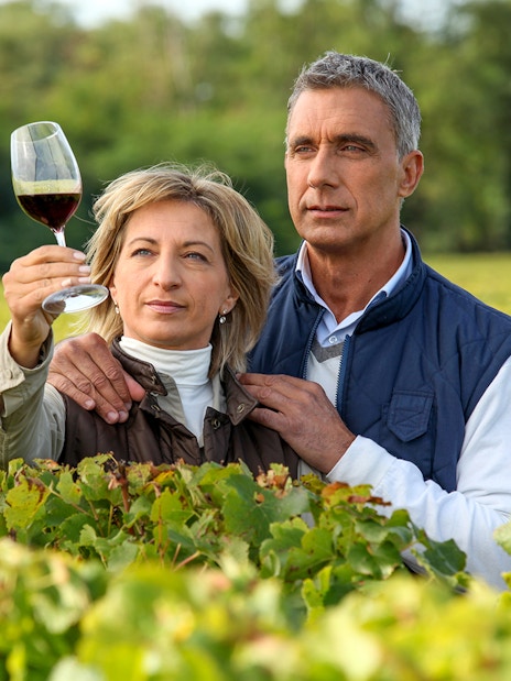 Couple examining wine in a vineyard during a wine tour.