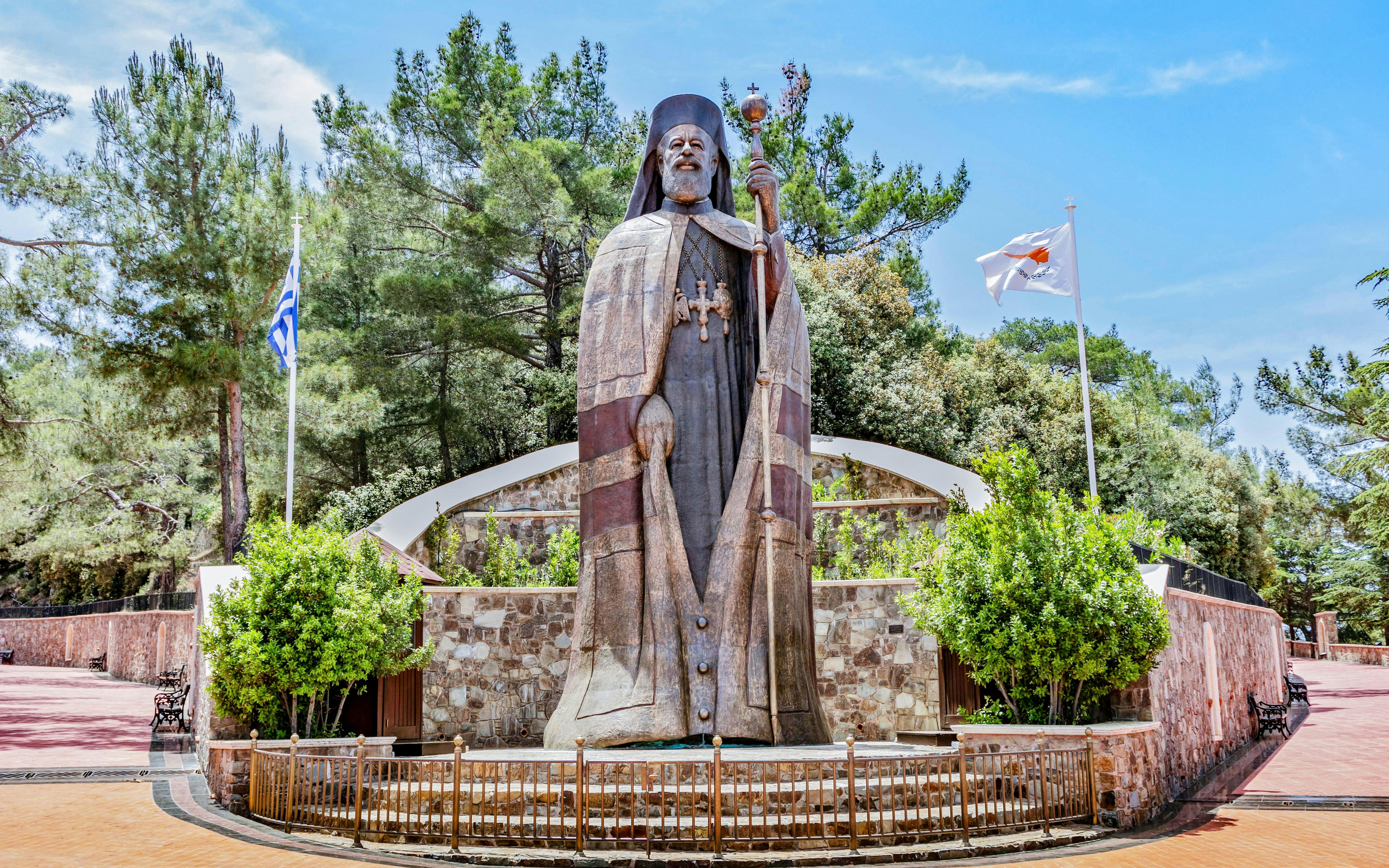 Monumental bronze statue of Makarios III in Troodos Mountains, Cyprus, with surrounding greenery.