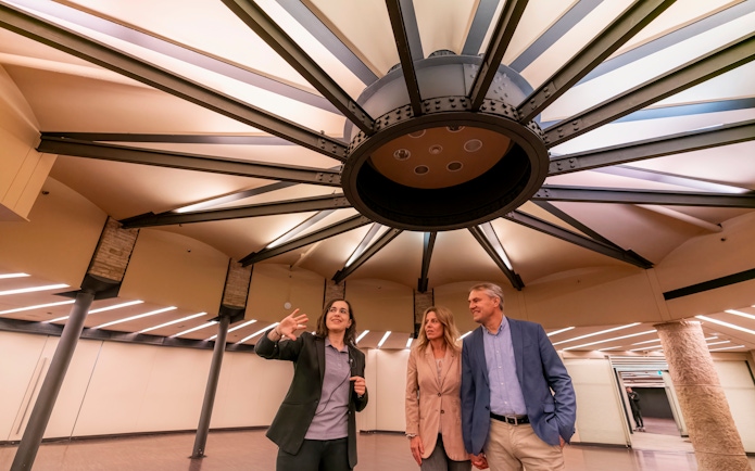 Tourist with guide examining ceiling design inside Casa Mila, Barcelona.