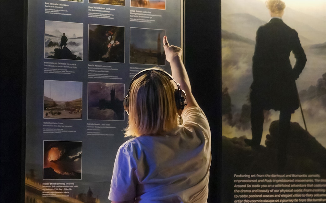 Guest exploring art display at Frameless London exhibition.