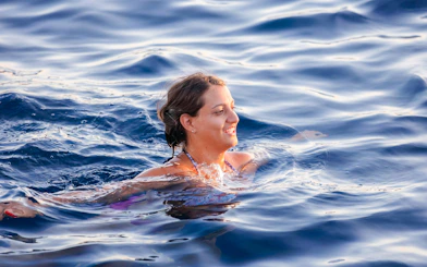 Person swimming in the ocean during a sunset catamaran cruise.