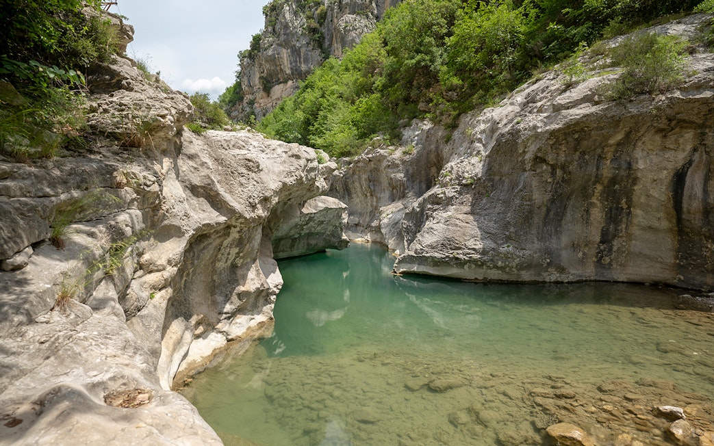 Bovilla Lake canyon with rocky cliffs and lush greenery during Gamti Mountain hiking tour.