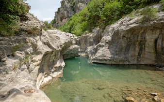 Bovilla Lake canyon with rocky cliffs and lush greenery during Gamti Mountain hiking tour.