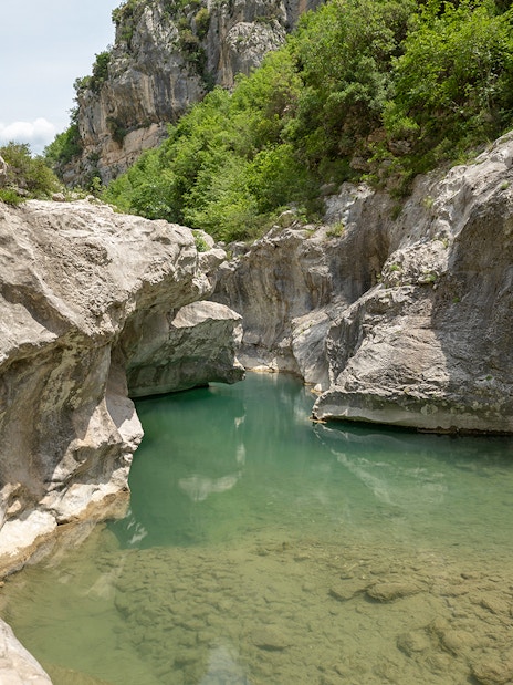 Bovilla Lake canyon with rocky cliffs and lush greenery during Gamti Mountain hiking tour.