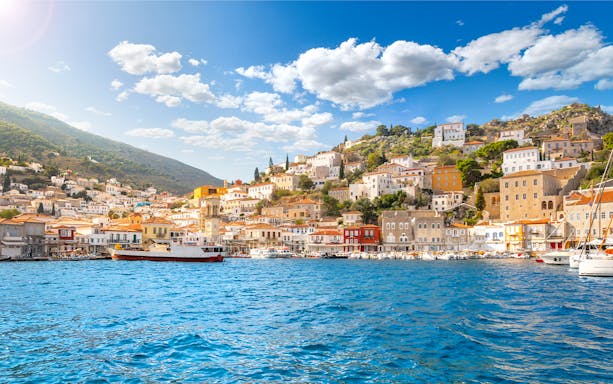 Hydra island waterfront with colorful buildings and boats, part of Athens island cruise.
