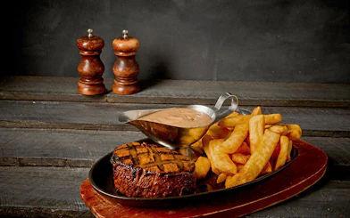 Steak and chips with sauce served on a wooden board, Cairns Aquarium Night Tour optional dinner.