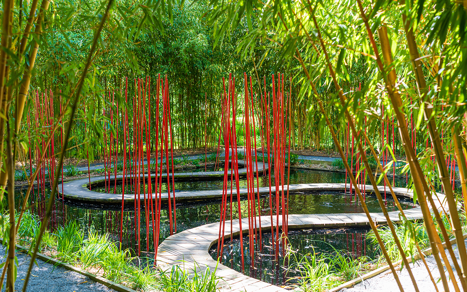 Curved wooden path with red poles in bamboo garden, Chaumont-sur-Loire Castle.