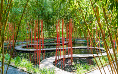 Curved wooden path with red poles in bamboo garden, Chaumont-sur-Loire Castle.