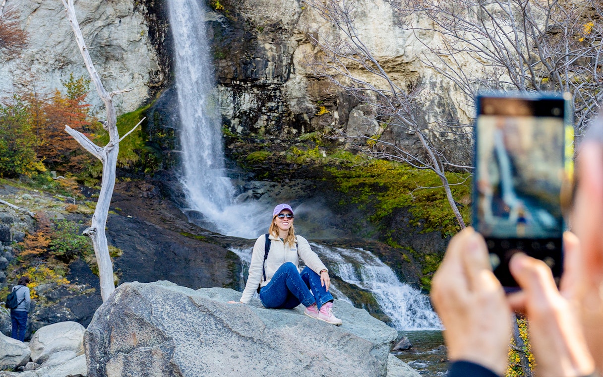 Tourist posing by a small waterfall in El Chaltén, Santa Cruz, Argentina.