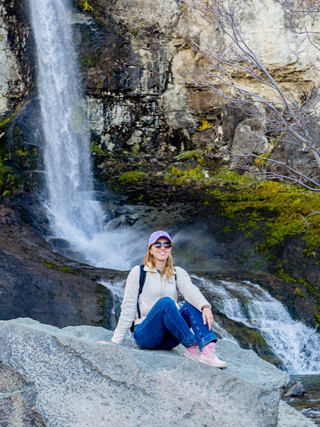 Tourist posing by a small waterfall in El Chaltén, Santa Cruz, Argentina.