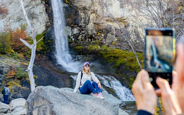 Tourist posing by a small waterfall in El Chaltén, Santa Cruz, Argentina.