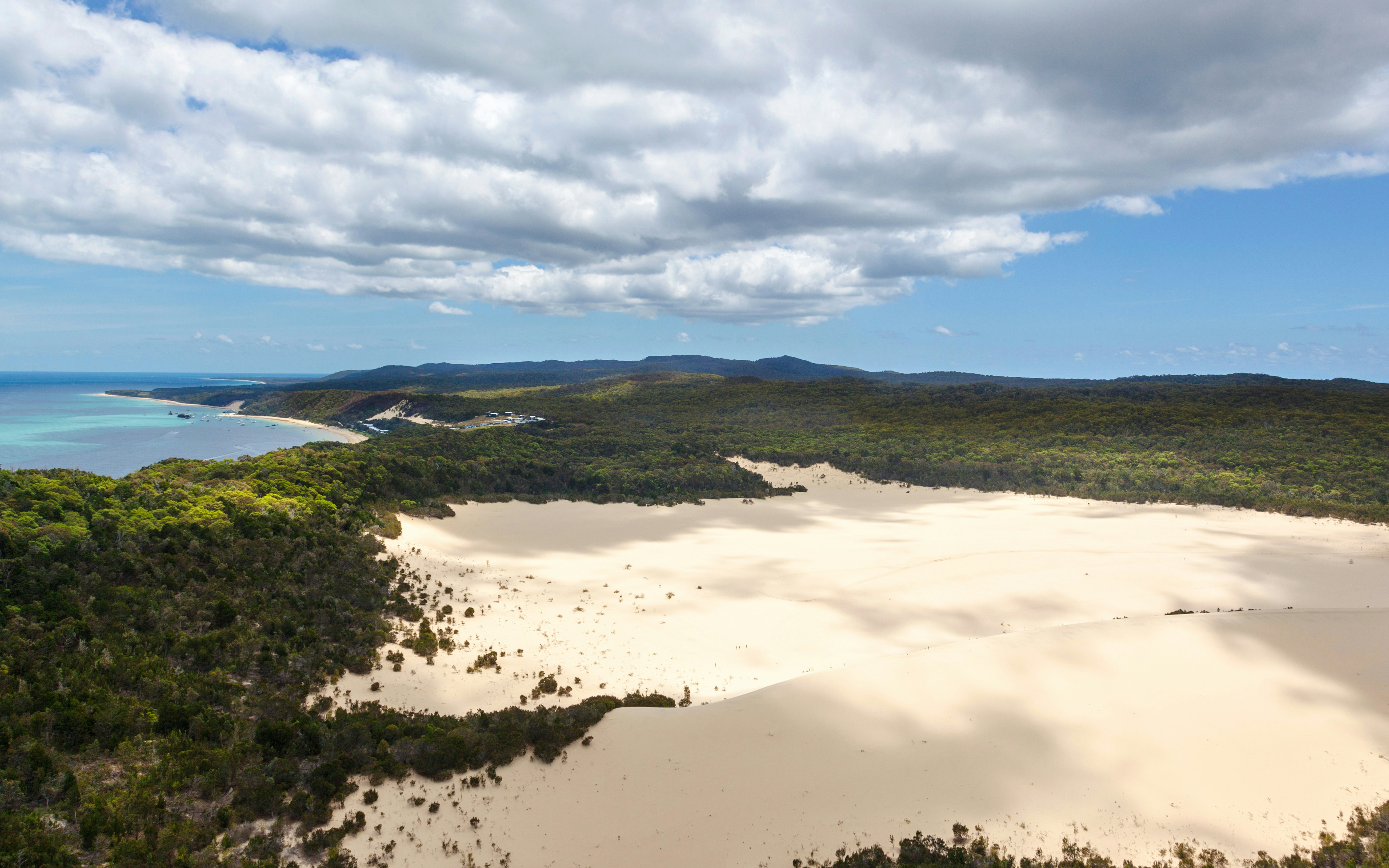 Sand dunes on Moreton Island with surrounding forest and coastline.