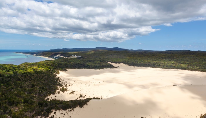 Sand dunes on Moreton Island with surrounding forest and coastline.