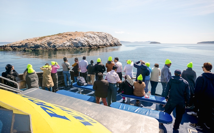 Group on a whale watching tour with Prince of Whales in Vancouver, viewing ocean and islands.