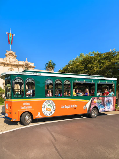Old Town Trolley with passengers in San Diego near historic building.