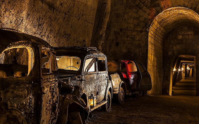 Abandoned vintage cars in the dimly lit Bourbon Tunnel, Naples.