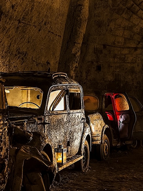 Abandoned vintage cars in the dimly lit Bourbon Tunnel, Naples.