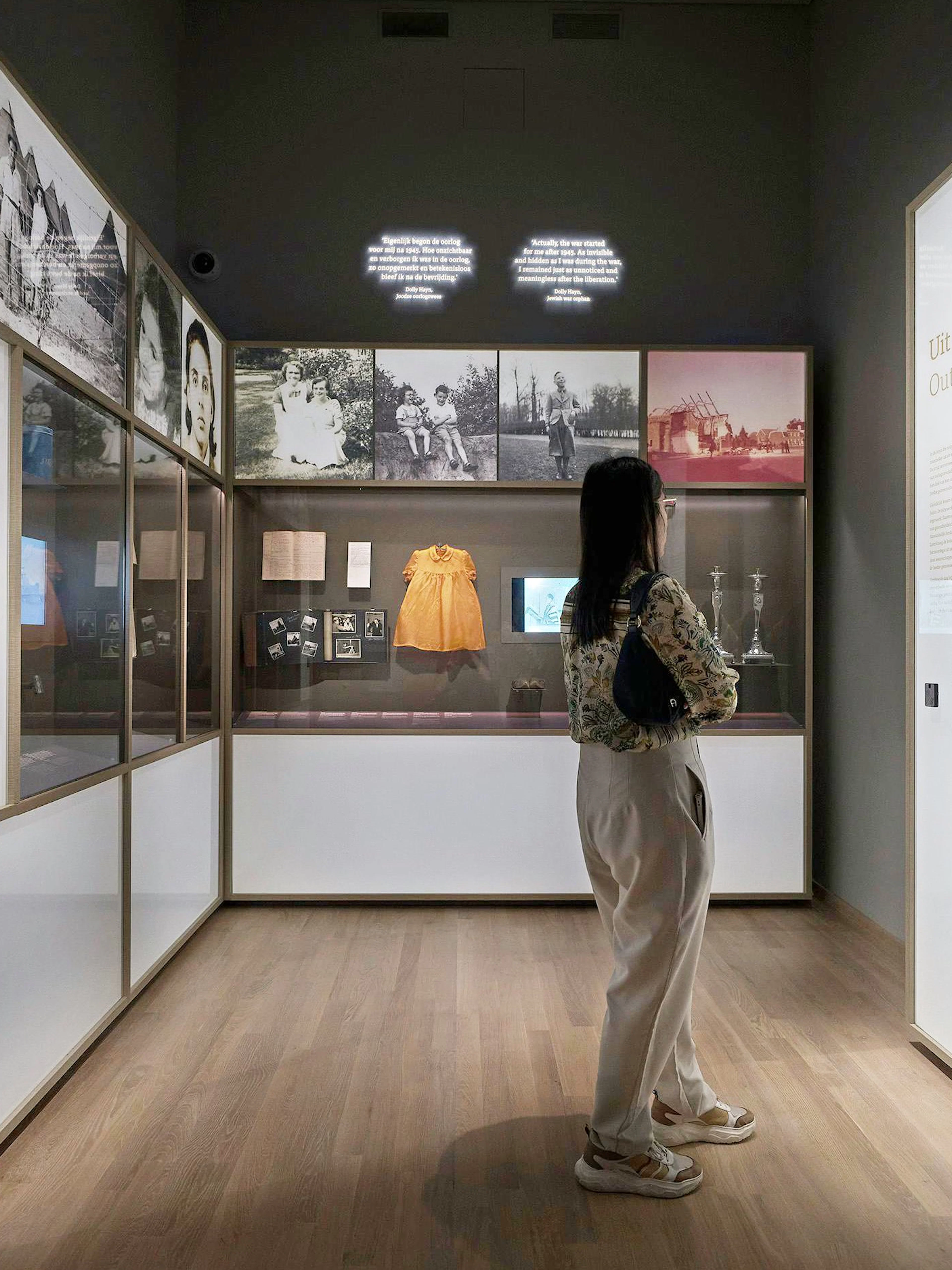 Visitor observing exhibits at the National Holocaust Museum, including historical photos and artifacts.