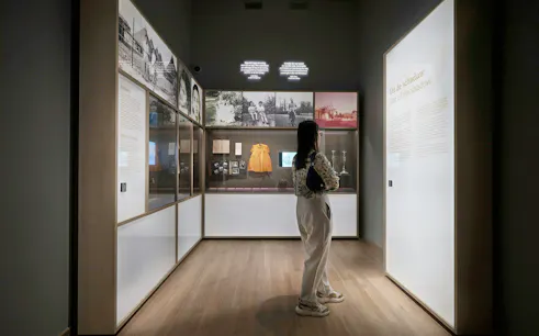 Visitor observing exhibits at the National Holocaust Museum, including historical photos and artifacts.