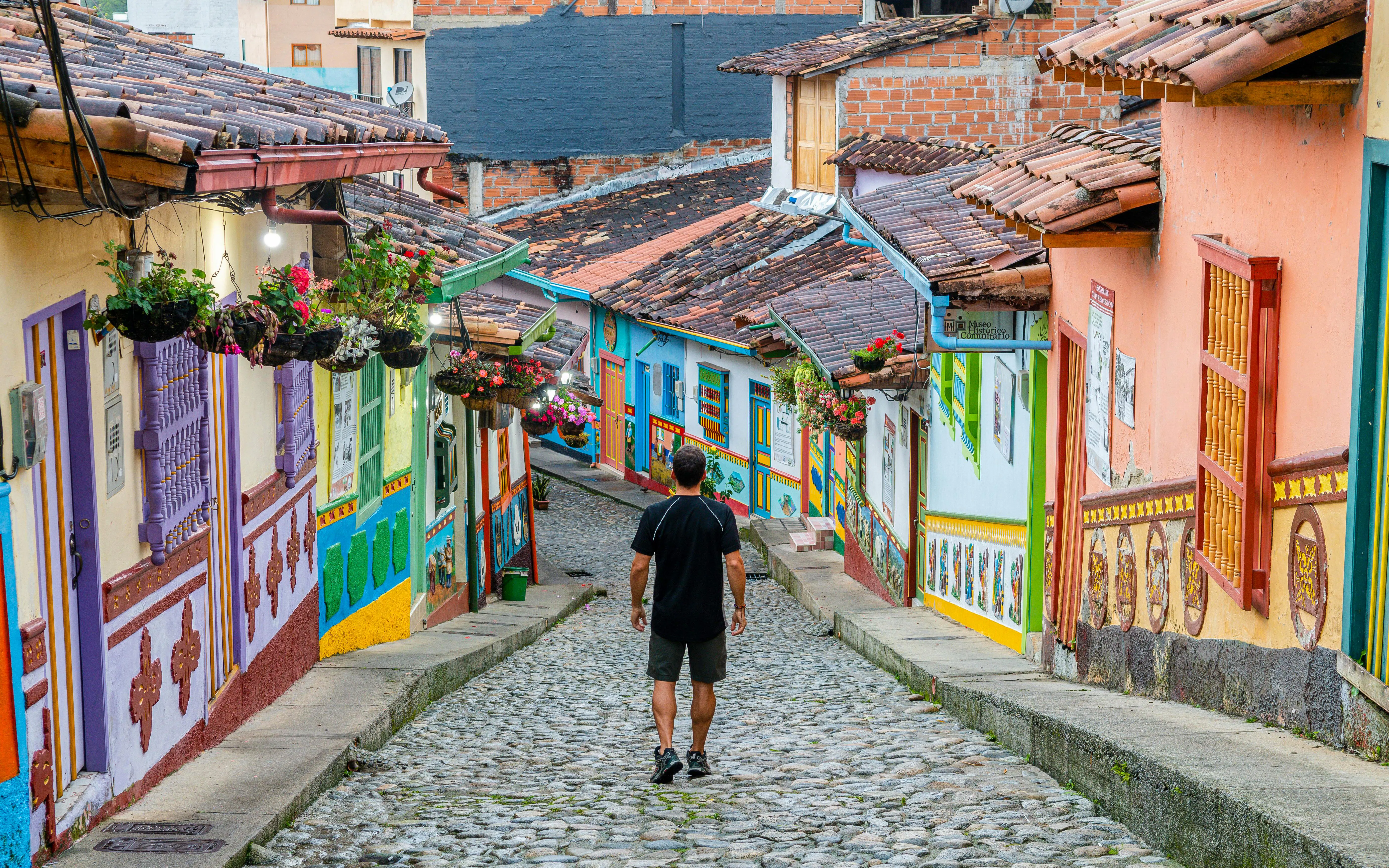Colorful cobblestone street in Guatape, Colombia, with vibrant colonial buildings and hanging flowers.
