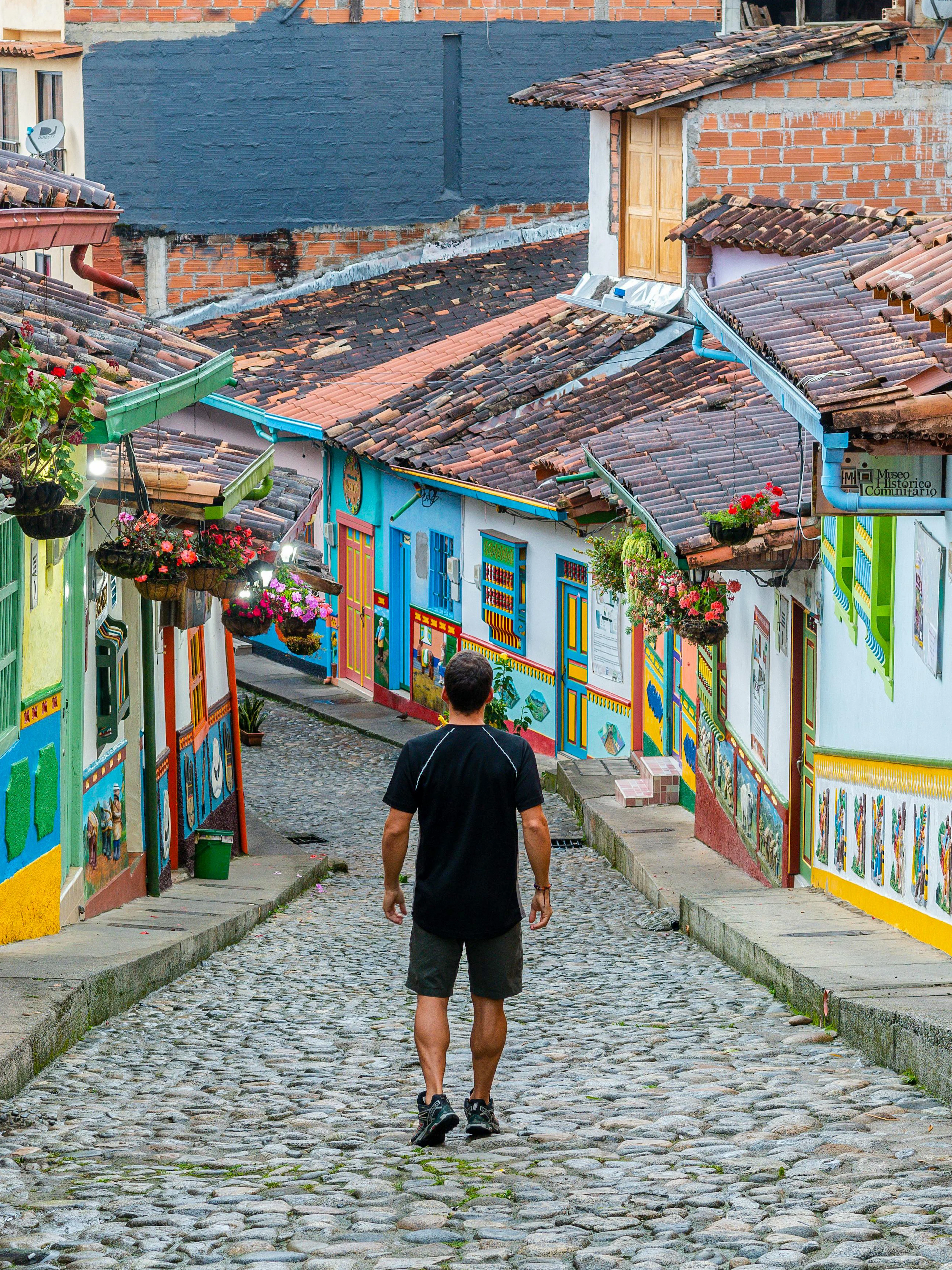 Colorful cobblestone street in Guatape, Colombia, with vibrant colonial buildings and hanging flowers.