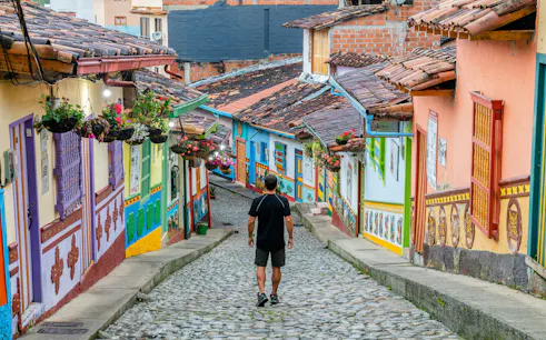 Colorful cobblestone street in Guatape, Colombia, with vibrant colonial buildings and hanging flowers.