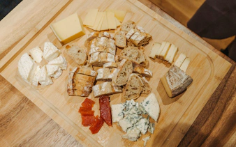 Assorted French cheeses and bread on a wooden board, part of the Ultimate Paris Food Tour.