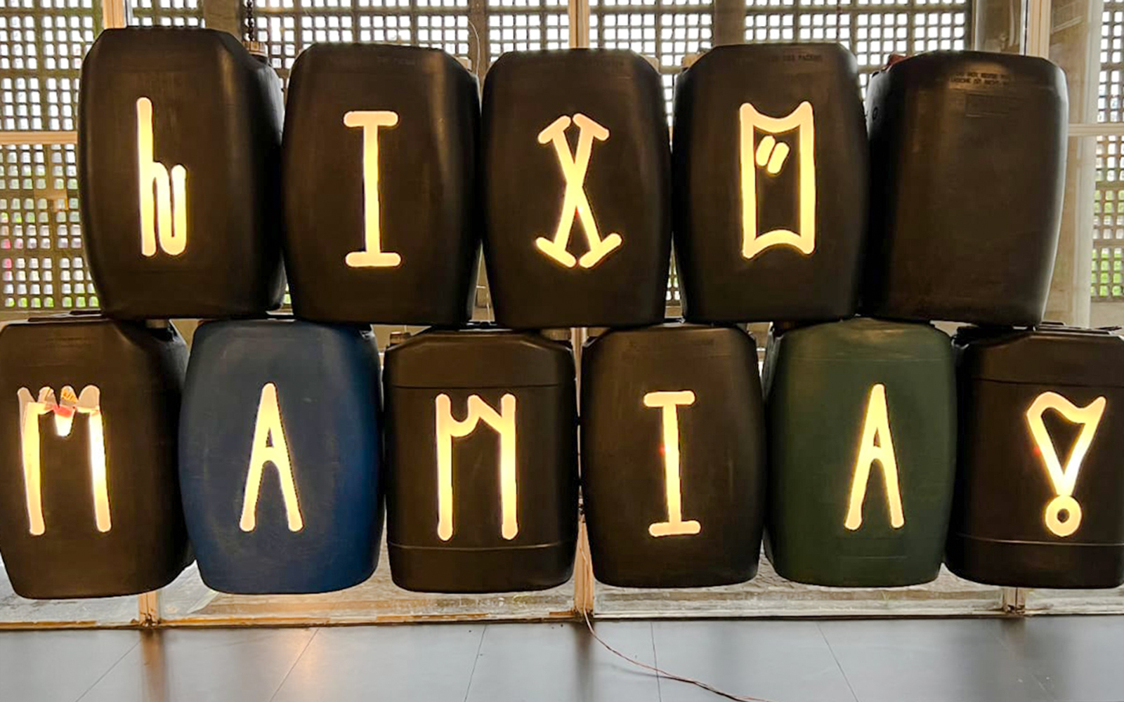 Barrels with illuminated symbols at Resistance and Rebellion exhibition, Straat Museum.