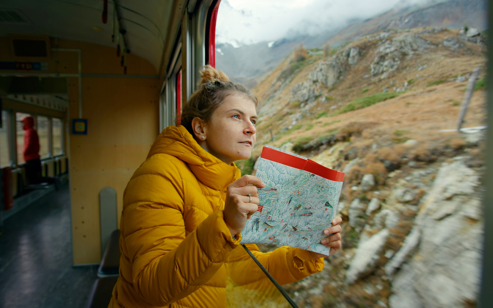 Woman holding a map, enjoying mountain views from Zermatt shuttle train.