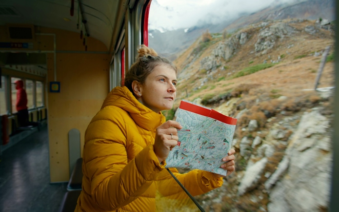 Woman holding a map, enjoying mountain views from Zermatt shuttle train.