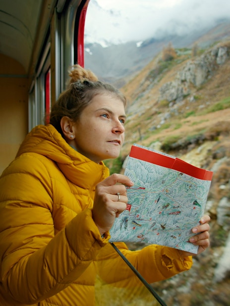 Woman holding a map, enjoying mountain views from Zermatt shuttle train.