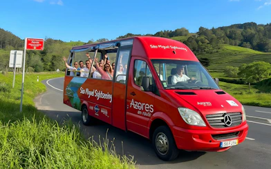 Hop-on hop-off bus with tourists on São Miguel road, Azores.