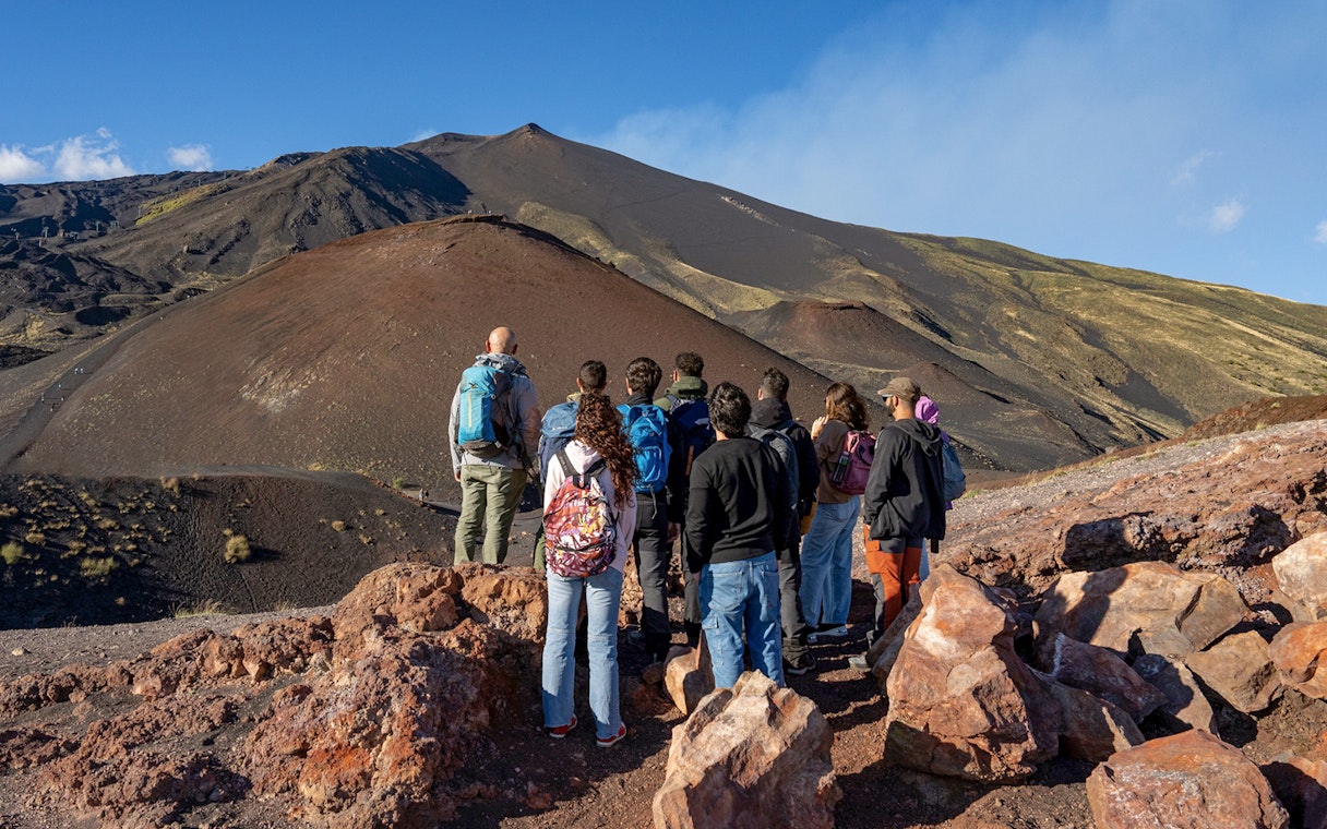 Tourists observing Mount Etna's volcanic landscape in Sicily.