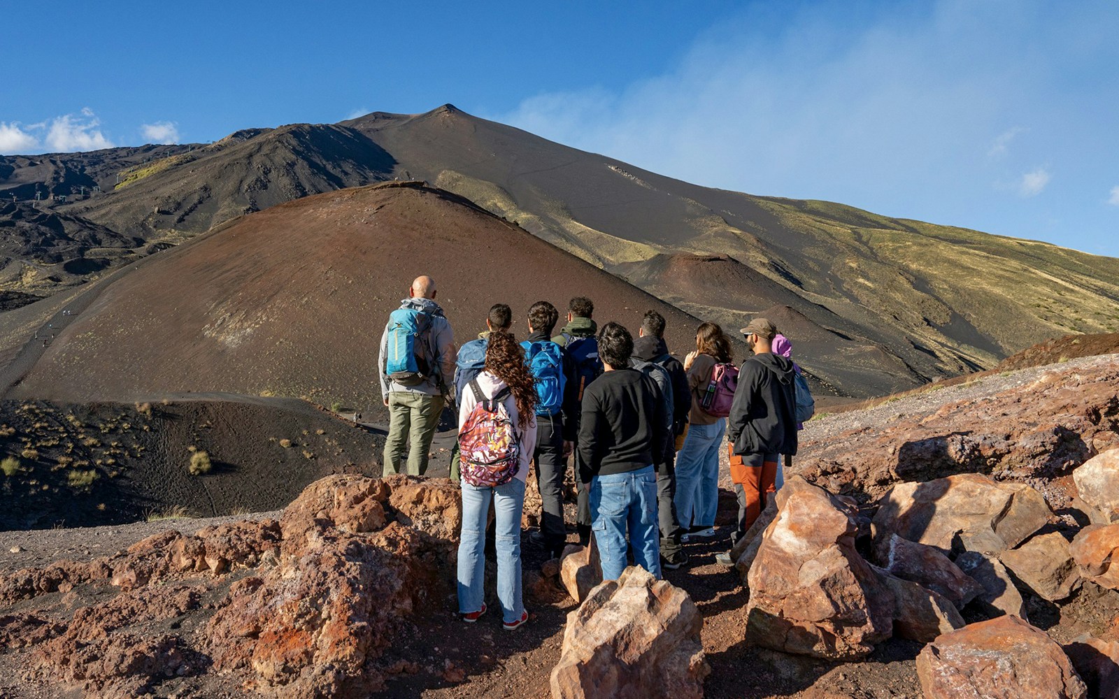 Tourists observing Mount Etna's volcanic landscape in Sicily.