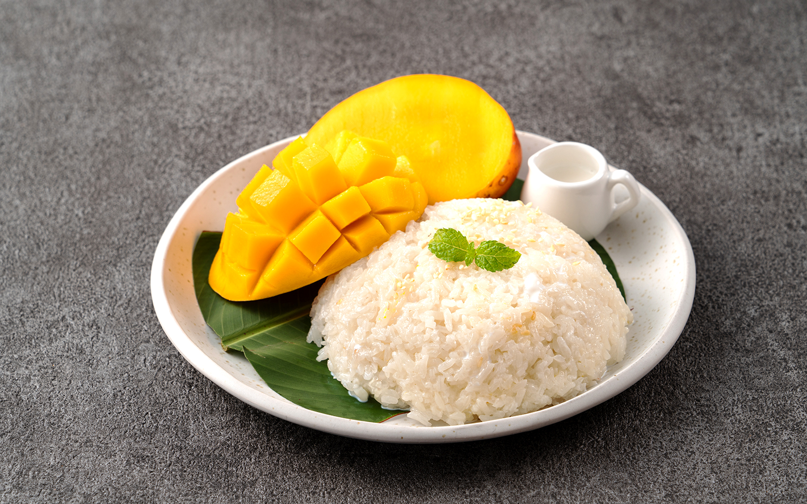 Mango sticky rice dessert on a plate with coconut sauce, Thailand.
